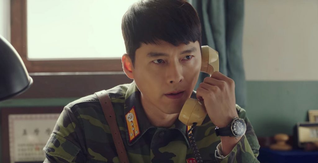 Captain Ri, holding up an old cord phone to his ear, looking exasperated