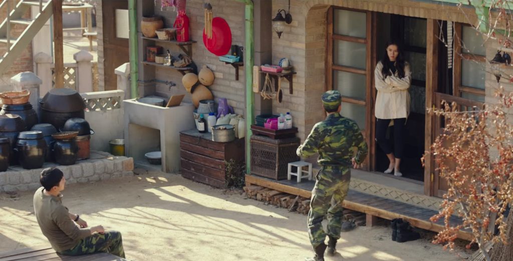 One of the soldiers is startled by Se-ri's sudden appearance from Captain Ri's house