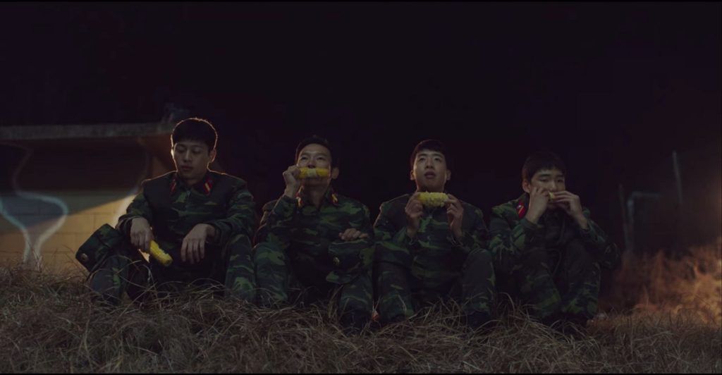 The four soldiers eating corn on the cob outside