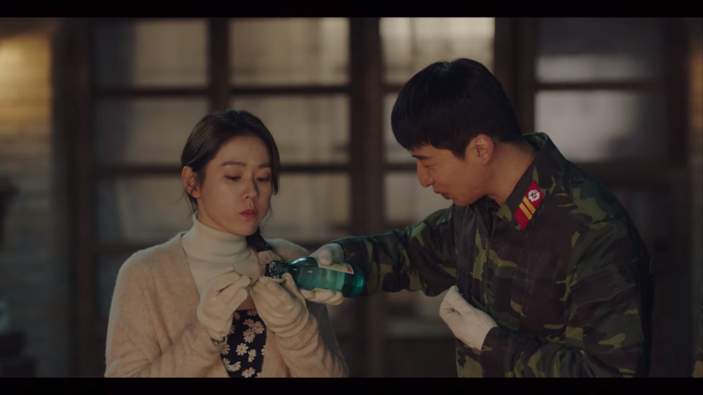 One of the soldiers pours shoju into Se-ri's clam shell